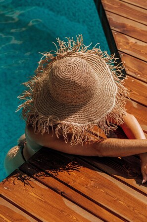A wooden deck by a pool with a straw hat on a chair. - Faro Punta Imperatore (Forio)