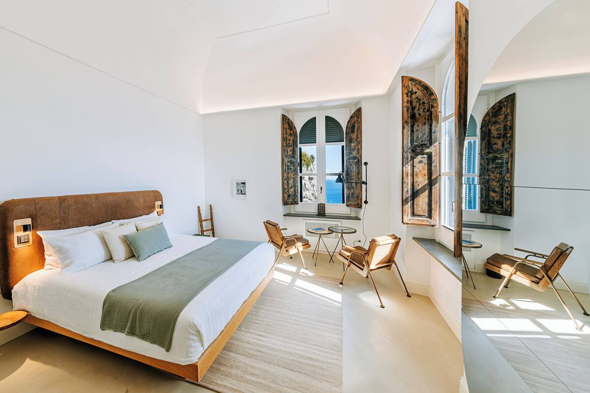 Quarto moderno com uma cama grande, uma mesa pequena e cadeiras.