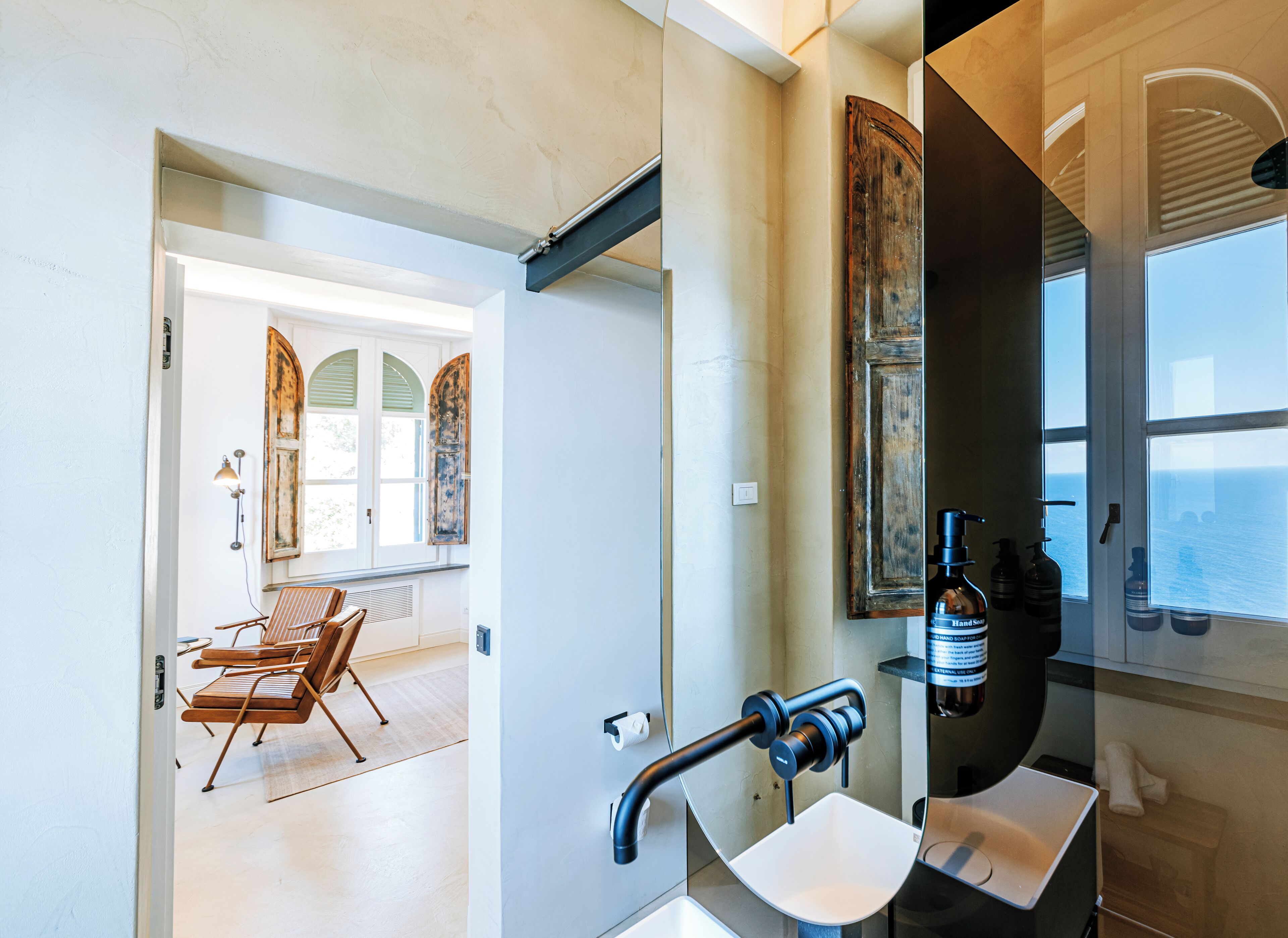 A modern bathroom with a large mirror, a sink, and a window.