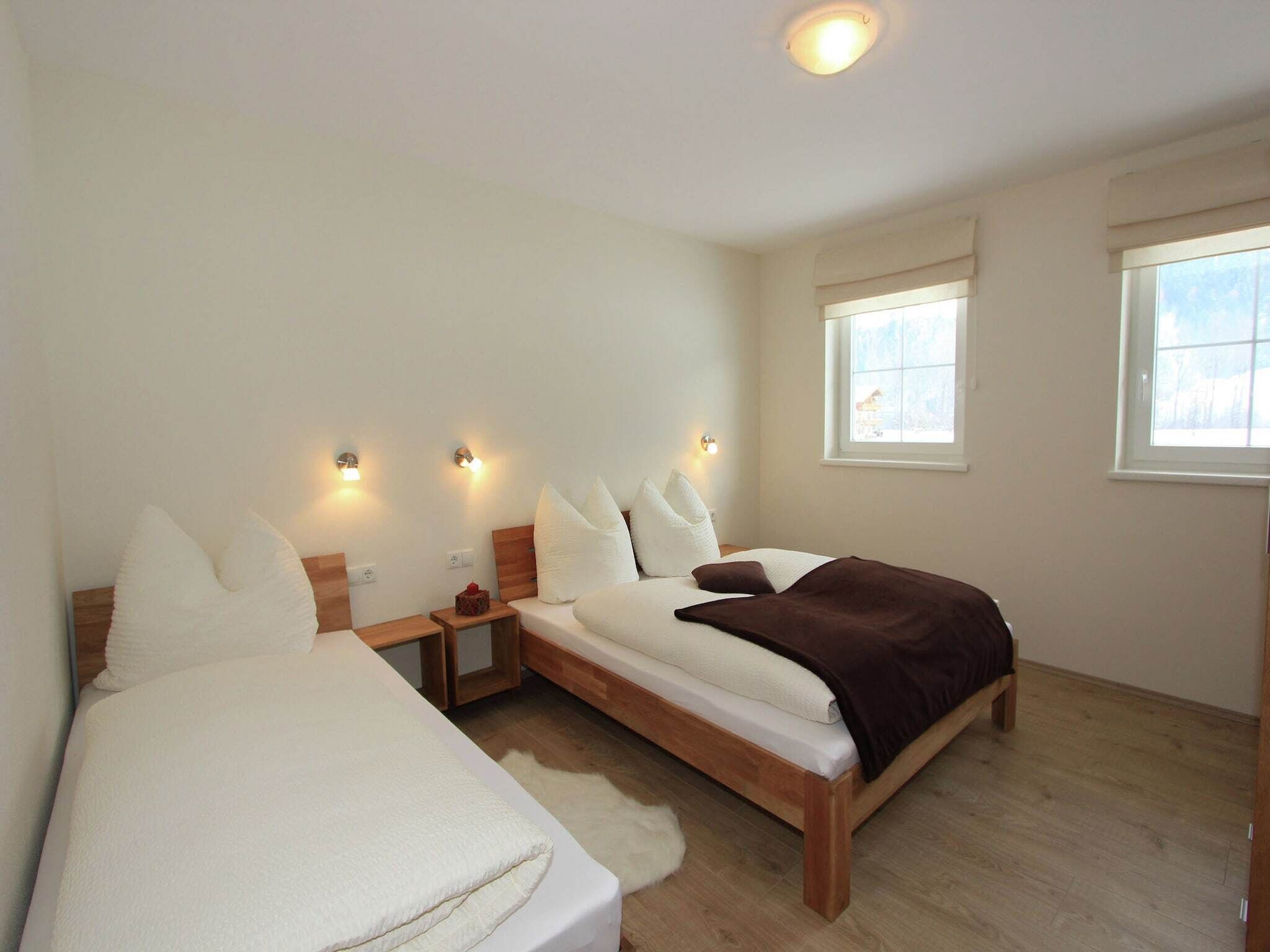 Une chambre avec deux lits, un plancher en bois et une grande fenêtre.