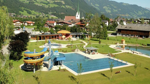 A resort with a swimming pool, water slides, and a view of a mountain town. - Apartment in Aschau near Hochzillertal Slopes (Aschau im Zillertal)