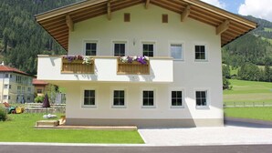 A two-story building with a sloped roof, multiple windows, and wooden balconies with flower boxes. - Apartment in Aschau near Hochzillertal Slopes (Aschau im Zillertal)