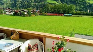 A terrace with a table, chairs, and a view of a green field and houses in the background. - Apartment in Aschau near Hochzillertal Slopes (Aschau im Zillertal)
