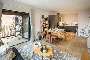 A modern apartment with a dining area, kitchen, and a balcony with a hanging chair. - 16 Minutes Walk To London Eye/shard View & Balcony (London)