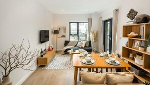A modern living room with a dining area, a sofa, a TV, and a bookshelf. - 16 Minutes Walk To London Eye/shard View & Balcony (London)
