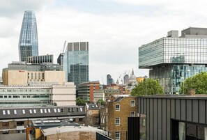 A cityscape with modern buildings, including a prominent glass skyscraper and a hotel with a flat roof. - 16 Minutes Walk To London Eye/shard View & Balcony (London)