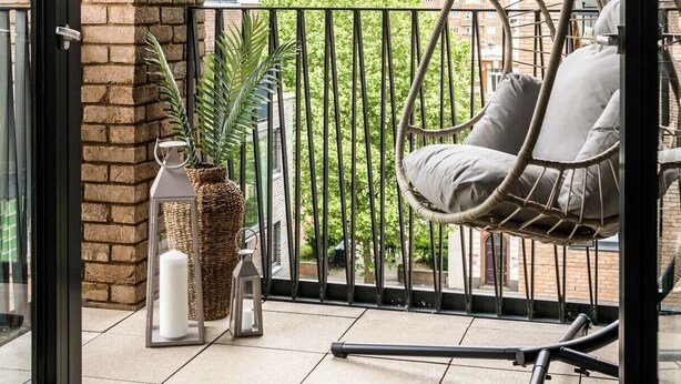 A balcony with a hanging chair, potted plants, and a view of a tall building. - 16 Minutes Walk To London Eye/shard View & Balcony (London)