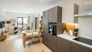 A modern kitchen with built-in appliances, a dining area with a sofa, and a view of the city. - 16 Minutes Walk To London Eye/shard View & Balcony (London)