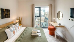 A modern bedroom with a large bed, a desk, a TV, and a view of the city through the window. - 16 Minutes Walk To London Eye/shard View & Balcony (London)