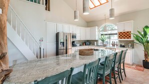 A kitchen with white cabinets, a granite countertop, and a central island with chairs. - Perfect Summer Lakefront Escape- Pool/Outdoor Kitchen & BBQ/Hot Tub/Fire Pit (Canyon Lake)