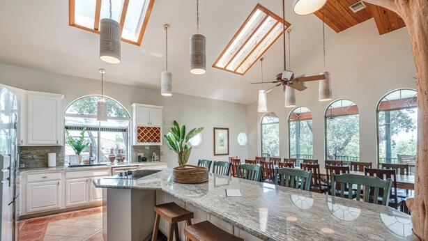 A spacious kitchen with a large island, wooden ceiling beams, and large windows. - Perfect Summer Lakefront Escape- Pool/Outdoor Kitchen & BBQ/Hot Tub/Fire Pit (Canyon Lake)