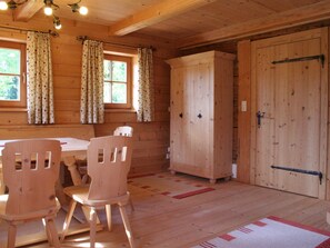 A wooden cabin interior with a dining table, two chairs, a cabinet, and a door. - Farmhouse in Hopfgarten near SkiWelt (Hopfgarten im Brixental)