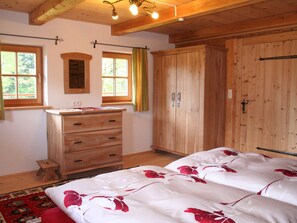 A bedroom with wooden furniture, a bed with a floral bedspread, a dresser, and a wardrobe. - Farmhouse in Hopfgarten near SkiWelt (Hopfgarten im Brixental)