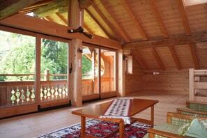 A wooden cabin with a large sliding glass door, a wooden table, and a bench. - Farmhouse in Hopfgarten near SkiWelt (Hopfgarten im Brixental)