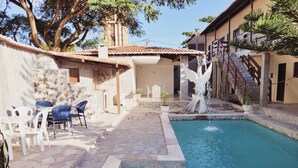A swimming pool with a fountain, outdoor seating, and a staircase leading to a building. - giuliano liciardi (Natal)