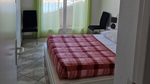 Une chambre d’hôtel avec un lit, une chaise, un bureau et une fenêtre avec des rideaux.