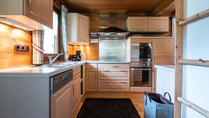 Una cocina compacta con armarios de madera, electrodomésticos de acero inoxidable y un tapete negro.