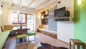 Ein gemütliches Wohnzimmer mit Holzboden, einer Steinwand und einem Flachbildfernseher, sowie einer grünen Wand.