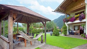 A wooden outdoor seating area with a hammock, a table, and chairs. - Apartment in Waidring near PillerseeTal Ski Area (Waidring)