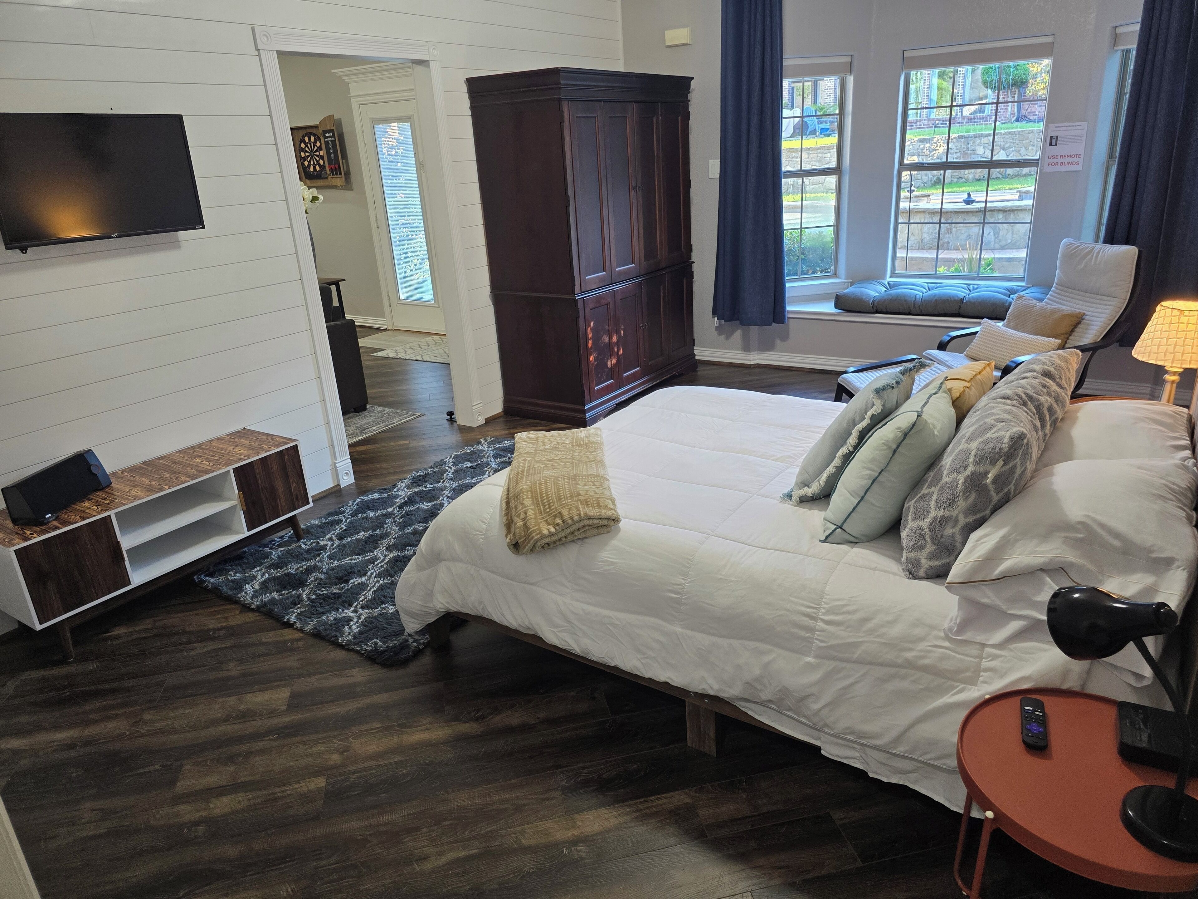 Une chambre avec un grand lit, une télévision, une armoire et une fenêtre donnant sur l’extérieur.