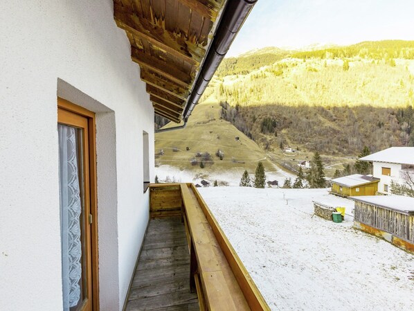 A balcony with a wooden floor and a view of a snowy landscape with houses and trees. - Apartment in See near Ski Slopes (See)