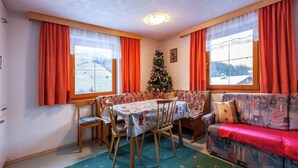 Een gezellige kamer met een eettafel, stoelen, een bank en een kerstboom.
