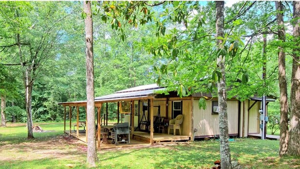 Un chalet rustique doté d’une véranda, d’un coin repas et d’une petite cuisine.
