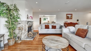 A living room with a fireplace, a sofa, a coffee table, and a large potted plant.