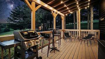 Une terrasse avec un barbecue, des chaises et une vue sur le ciel nocturne.
