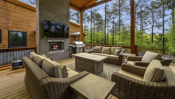 An outdoor deck with wicker furniture, a fire pit, and a grill. - Ring of Fire -5 Master Suites,Sleeps 24-Basketball Ct & More! (Broken Bow)