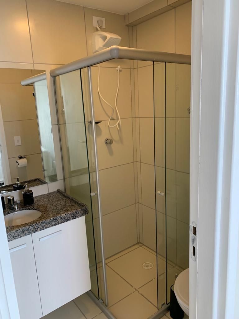 A bathroom with a glass shower enclosure, a sink with a granite countertop, and a toilet.
