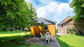 A small wooden house with a patio, surrounded by a well-maintained lawn and trees. - Charming Chalet in Vielsalm (Vielsalm)