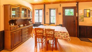 A dining area with a wooden table, two chairs, and a cabinet with glass doors.