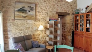 Una sala de estar con una pared de piedra, un sofá, una lámpara, un aparador de madera y un cuadro.