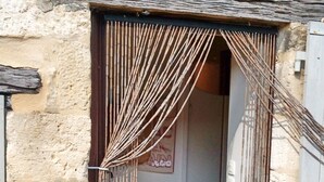 Fachada de un edificio de piedra con una puerta de madera y una cortina de bambú.