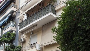 A multi-story residential building with balconies, air conditioning units, and potted plants. - Classic Koukaki Living 2 Bd with Balcony (Athens)