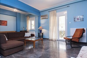A living room with a brown sofa, a wooden coffee table, a blue vase, and a patterned orange chair. - Classic Koukaki Living 2 Bd with Balcony (Athens)