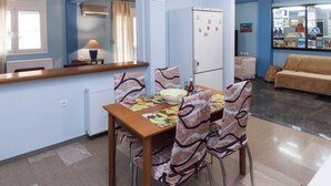 A dining area with a table set for four, chairs with patterned upholstery, a bowl of fruit, and a lamp on the table. - Classic Koukaki Living 2 Bd with Balcony (Athens)