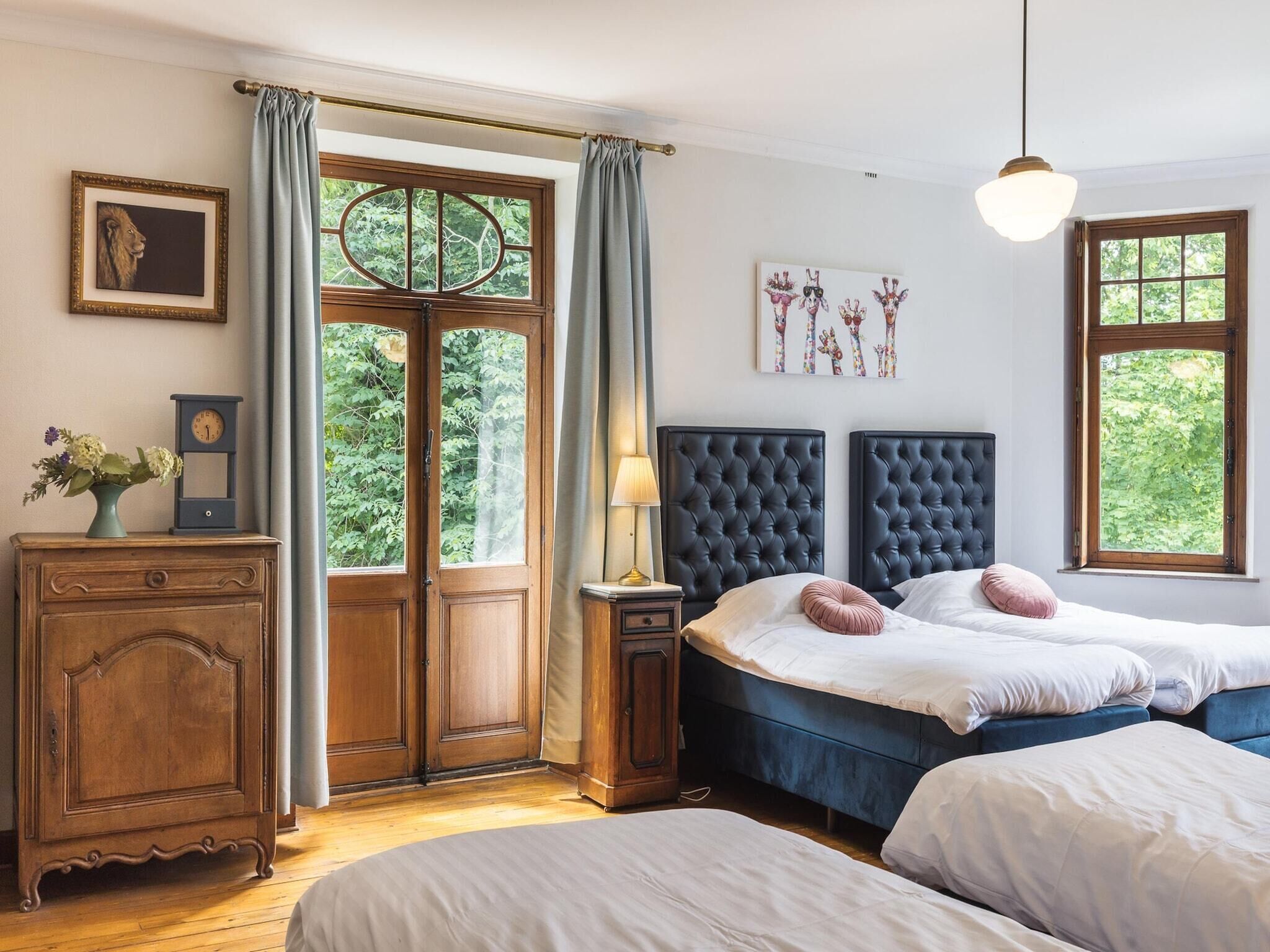 A bedroom with two beds, a wooden dresser, a clock, and a window with curtains.
