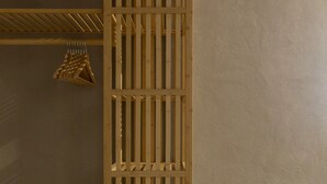 Een houten wandplank met verschillende vakken, een geweven mandje dat aan een van de planken hangt, en een effen muur op de achtergrond.