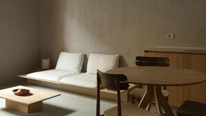 Een minimalistisch ingerichte kamer met een bank, een kleine tafel en een ronde tafel.