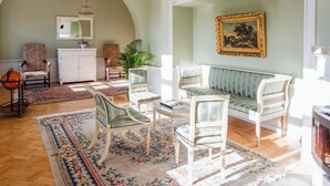 A spacious living room with a classic design, featuring a sofa, chairs, a coffee table, and a fireplace. - A grand, newly renovated villa in a castle setting (Stora Sundby)