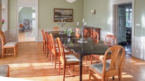 A dining room with a large table, wooden chairs, a chandelier, and a painting on the wall. - A grand, newly renovated villa in a castle setting (Stora Sundby)