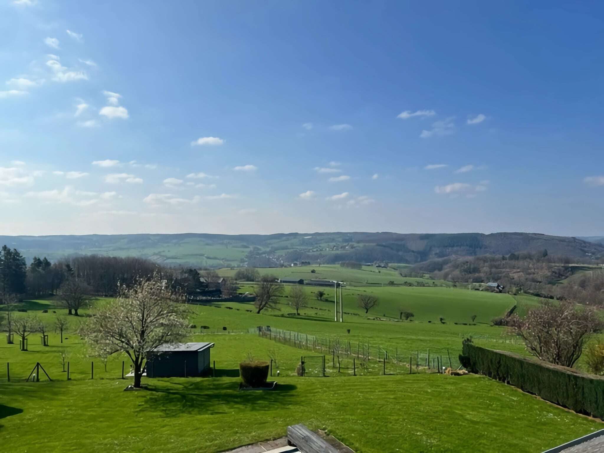 A rural landscape with rolling hills, a fenced field, and a small shed.