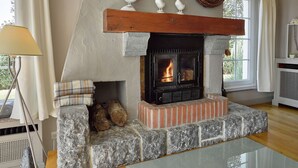 A cozy room with a stone fireplace, a wooden mantel, and decorative bird figures. - Scenic Theux Retreat with Pool & Garden. (Theux)