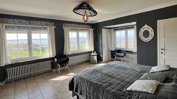 A bedroom with a large bed, two windows with curtains, a radiator, a desk, and a chair. - Scenic Theux Retreat with Pool & Garden. (Theux)