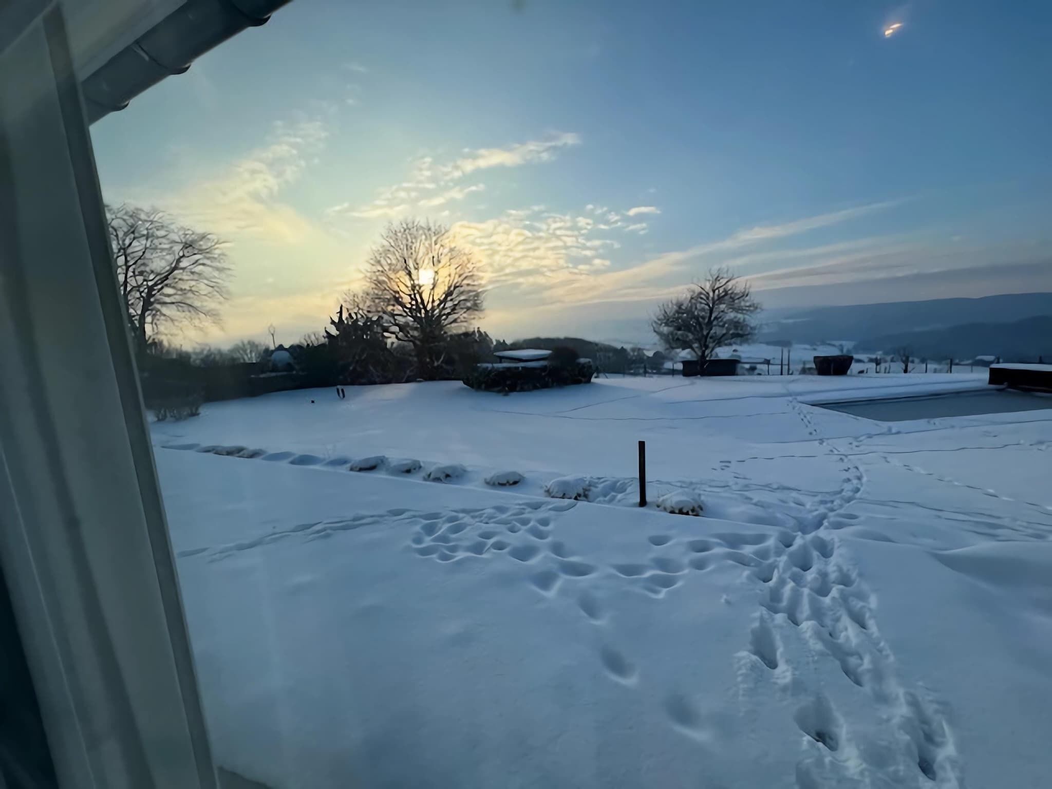 A snowy landscape with footprints leading to a building.
