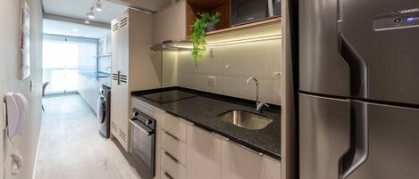Una cocina moderna con electrodomésticos de acero inoxidable, horno empotrado y pileta.