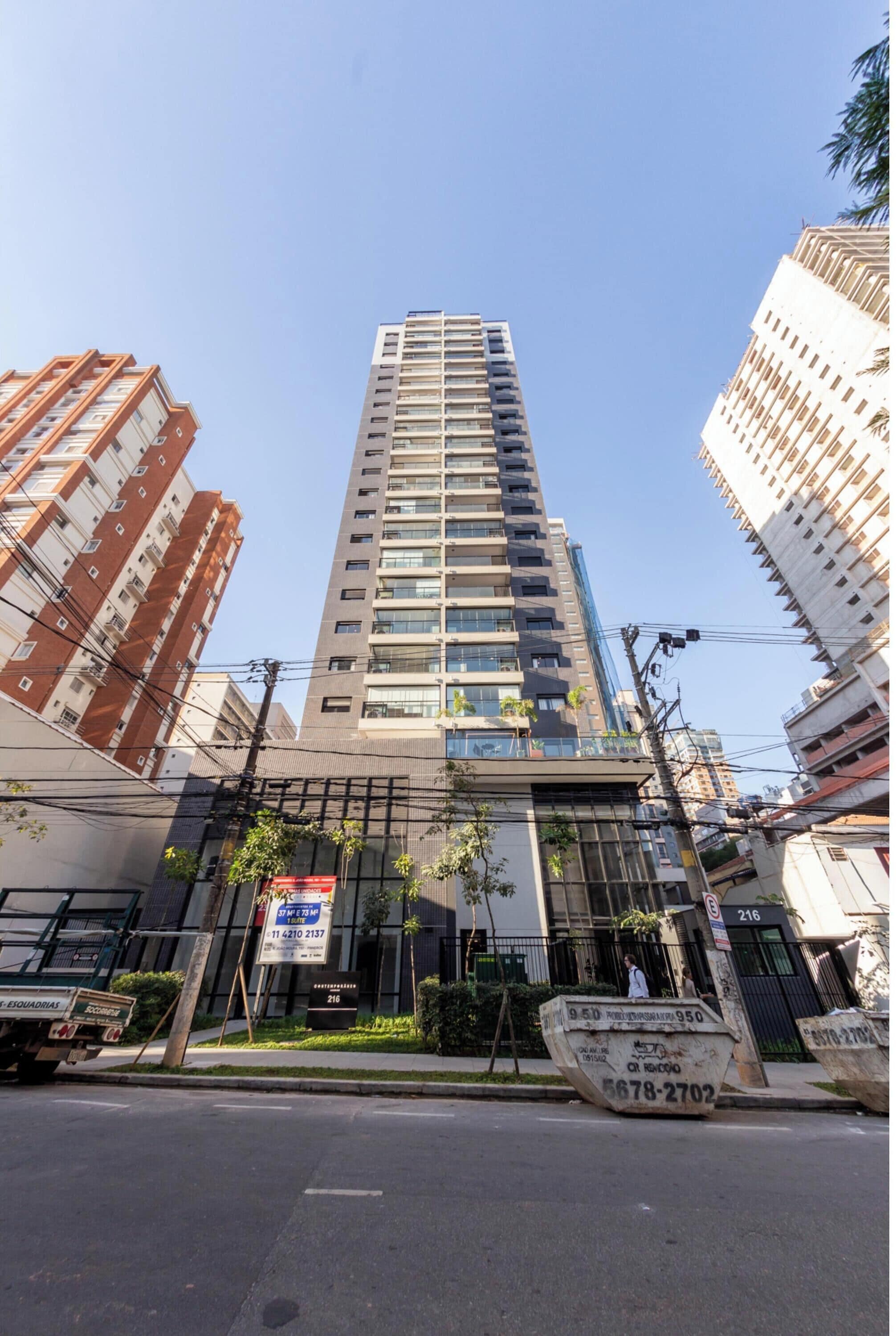 A tall, modern building with multiple floors, surrounded by other high-rise buildings.