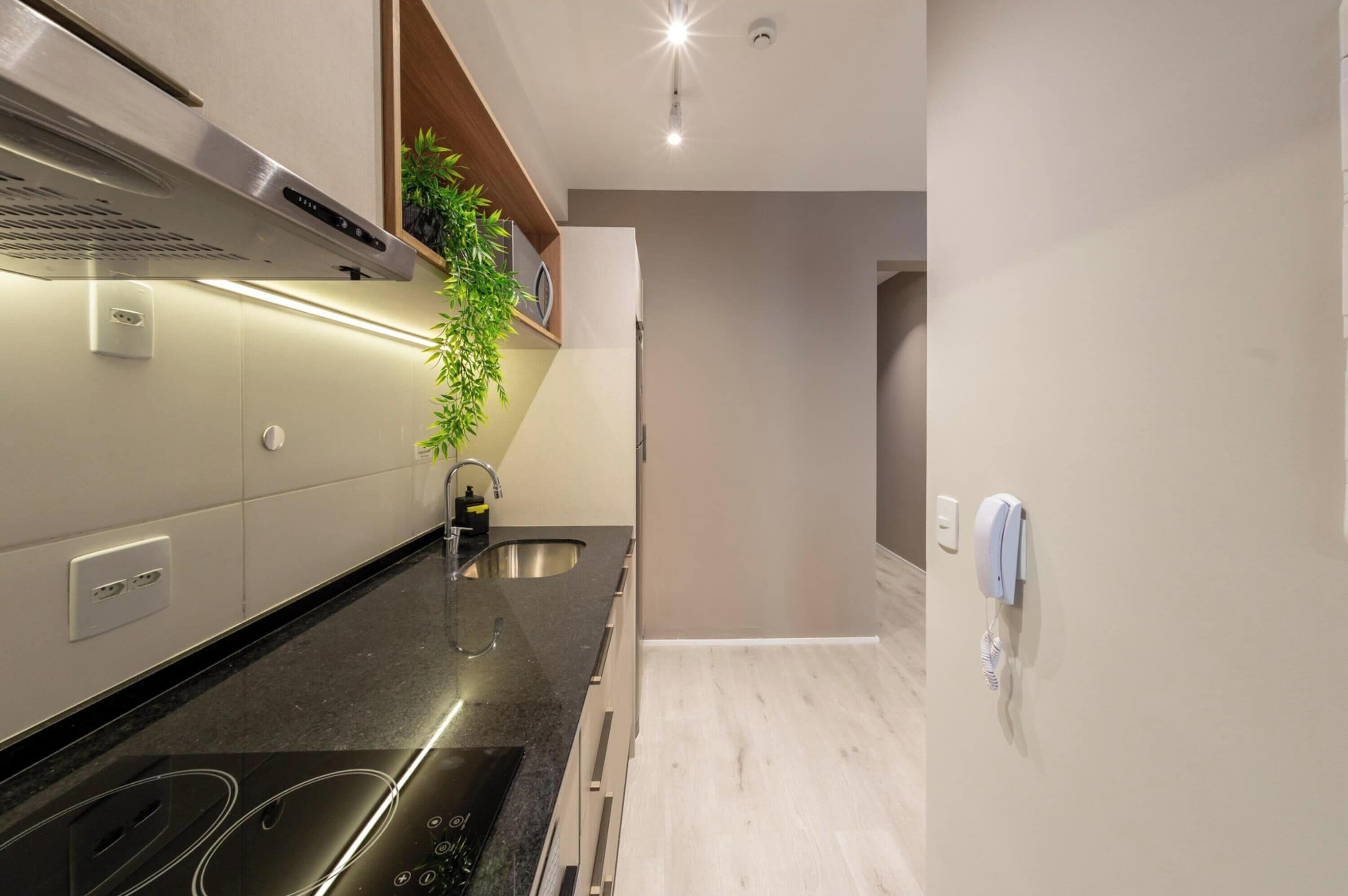 A modern kitchen with a black countertop, stainless steel sink, and a built-in oven.